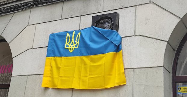 Стіна, меморіальна дошка та державний прапор України